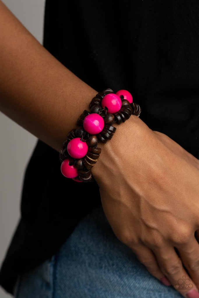 Oversized pink wooden beads, rustic brown wooden beads, and dainty wooden discs are ornately threaded along braided stretchy bands around the wrist, creating a summery centerpiece.  Sold as one individual bracelet.